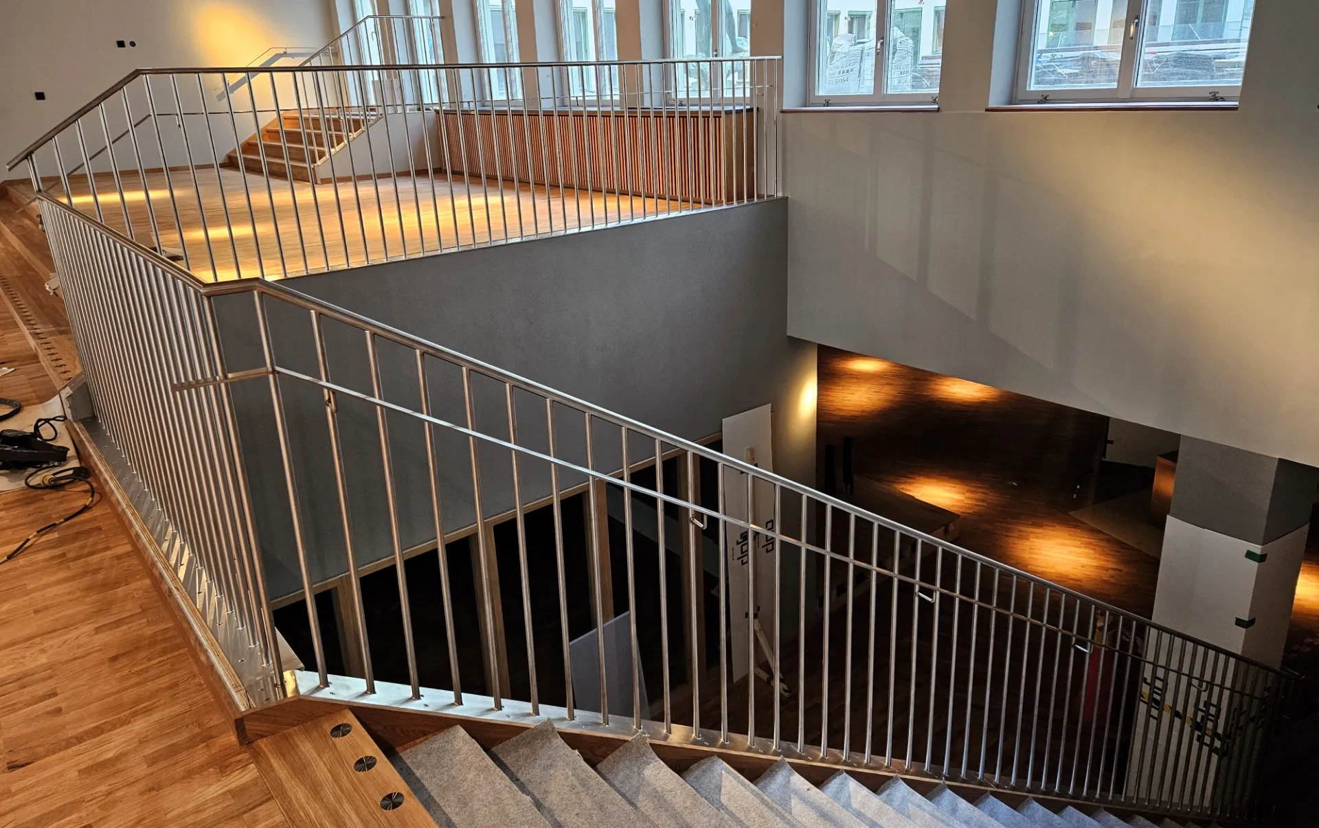 Rostfria räcken kring ett stort trapphus med ektrappor