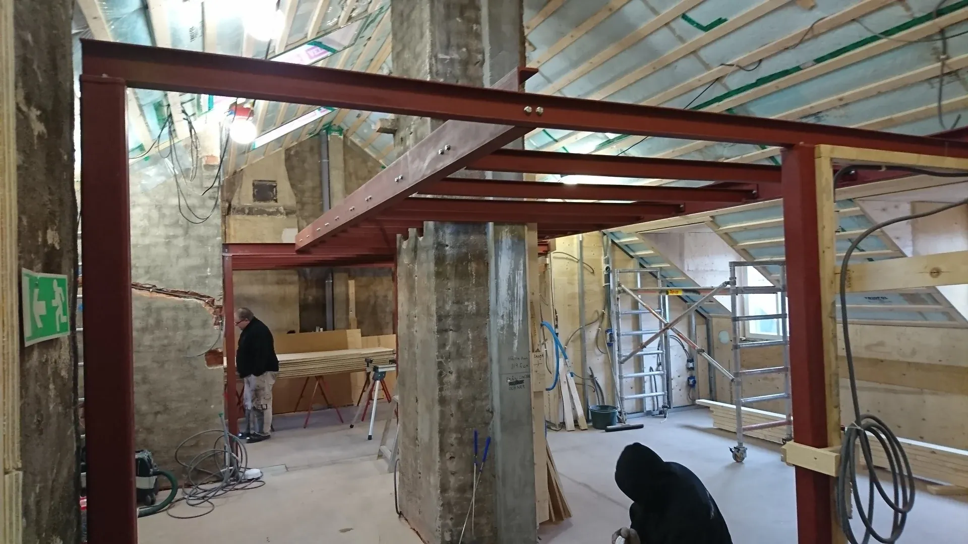 Rödgrundade stålbalkar till en loftkonstruktion under byggnation